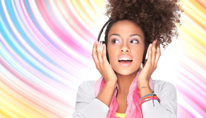 young woman listening to music on headphones on colorful background