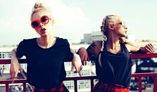 Two Sisters hanging out wearing black t-shirts and red skirts