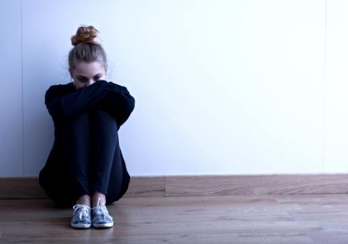 Girl sad and sitting on the floor with her head in her hands after a break up for a post about breakup songs